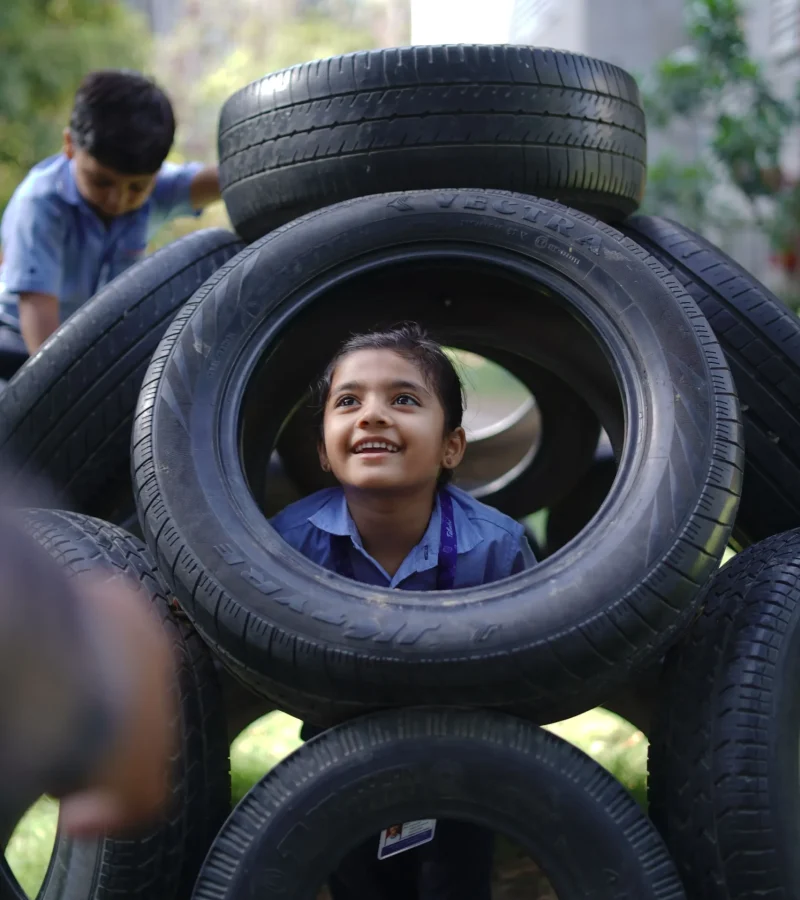 Girl Peeking Through Tire Play
