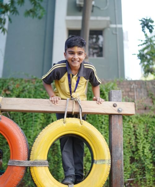 Young Student Playing on Wooden Tire Obstacle Course at School Playground Lawn