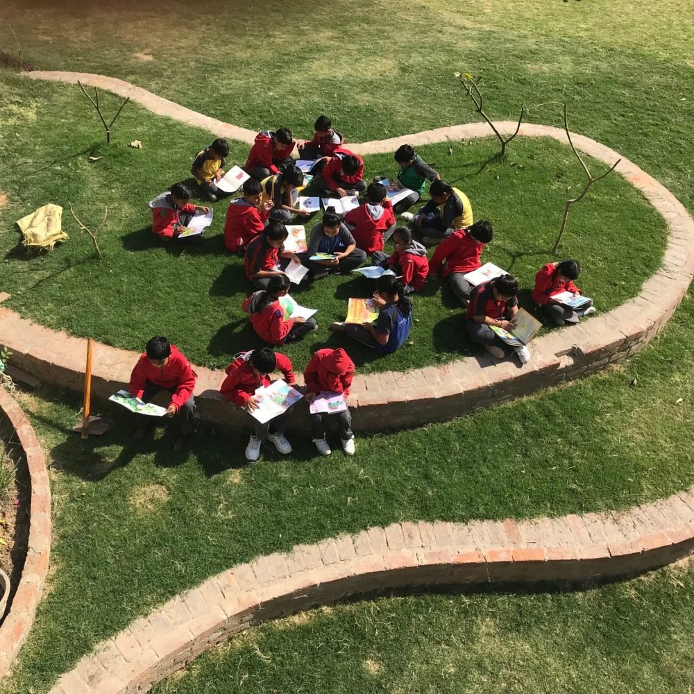 Students Reading Books Outdoors on School Lawn