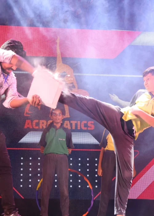 Young Student Performing Martial Arts Board Break on Stage During Acrobatics Demonstration